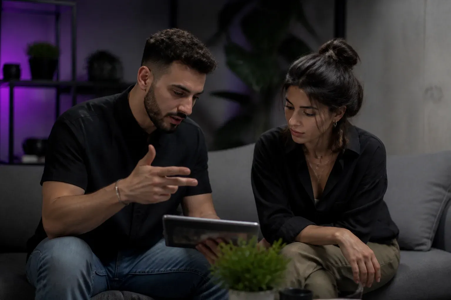 שני אנשים יושבים על ספה במשרד קטן ומתכננים יחד עם טאבלט ביניהם
